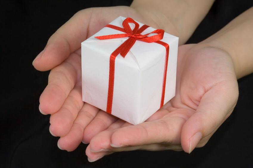 Hands holding a gift box isolated on black background