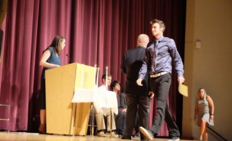 Students walk across the auditorium stage to shake hands with Principal Mark Fletcher. The new inductees received certificates and carnations. 