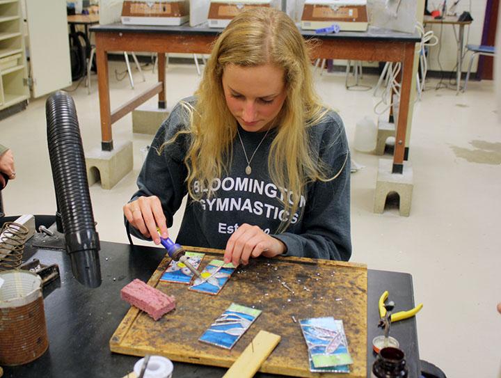 Student solders during stained glass