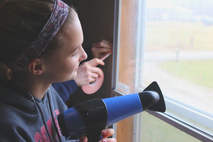 Junior Tamsin Stringer blow dries plastic onto a window