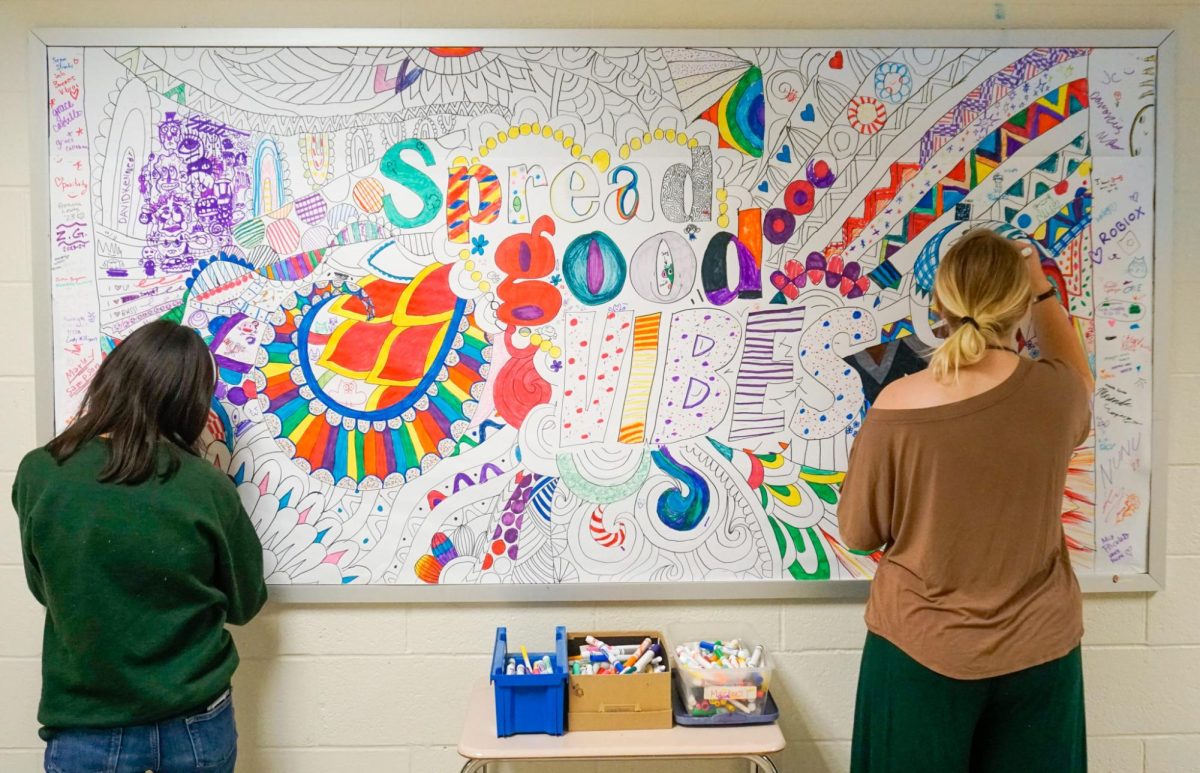 People work on collaborative art board in hallway.