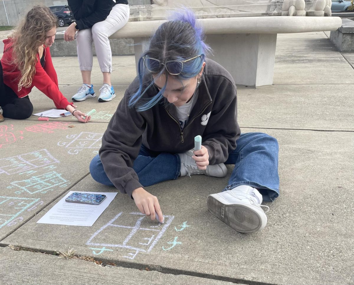 Senior, Katie Summerlot, draws punnet squares with chalk for Mrs. Wenning’s genetics class