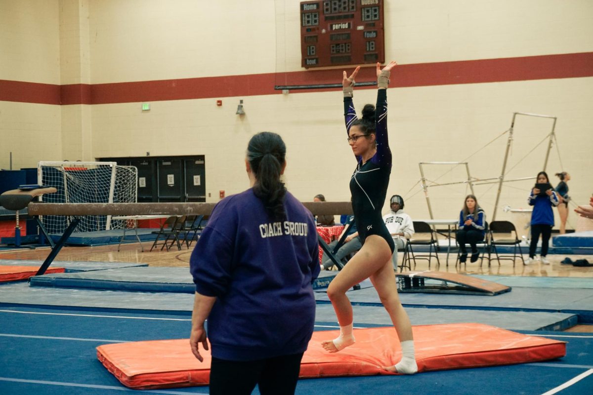 Bloomington South gymnastics Head Coach Michelle Stroud looks on as senior captain Stella Eilbilng completes the first tumbling pass in her routine