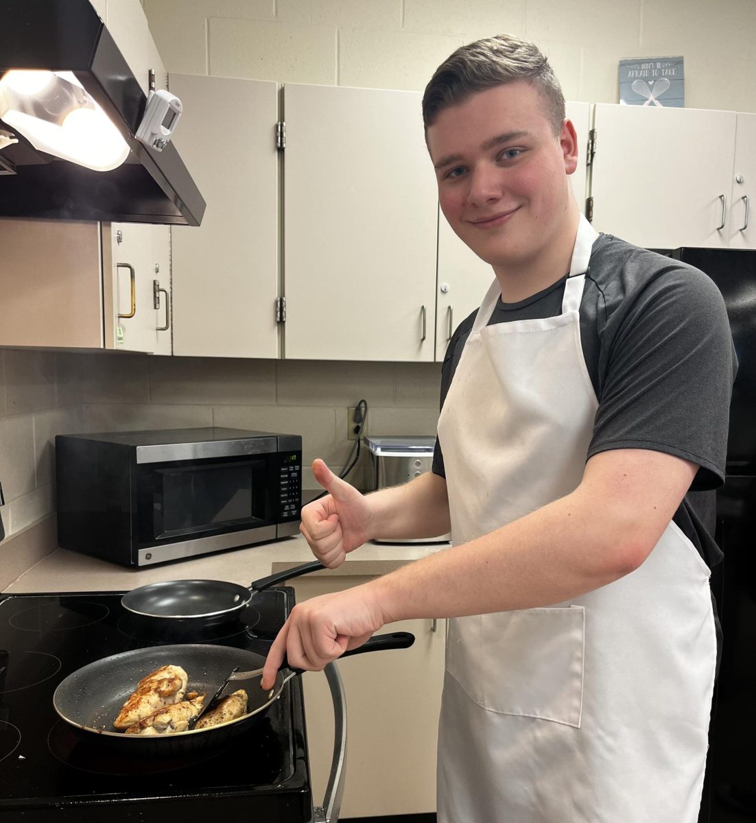 Junior Kylan Guidry cooks chicken in cooking class